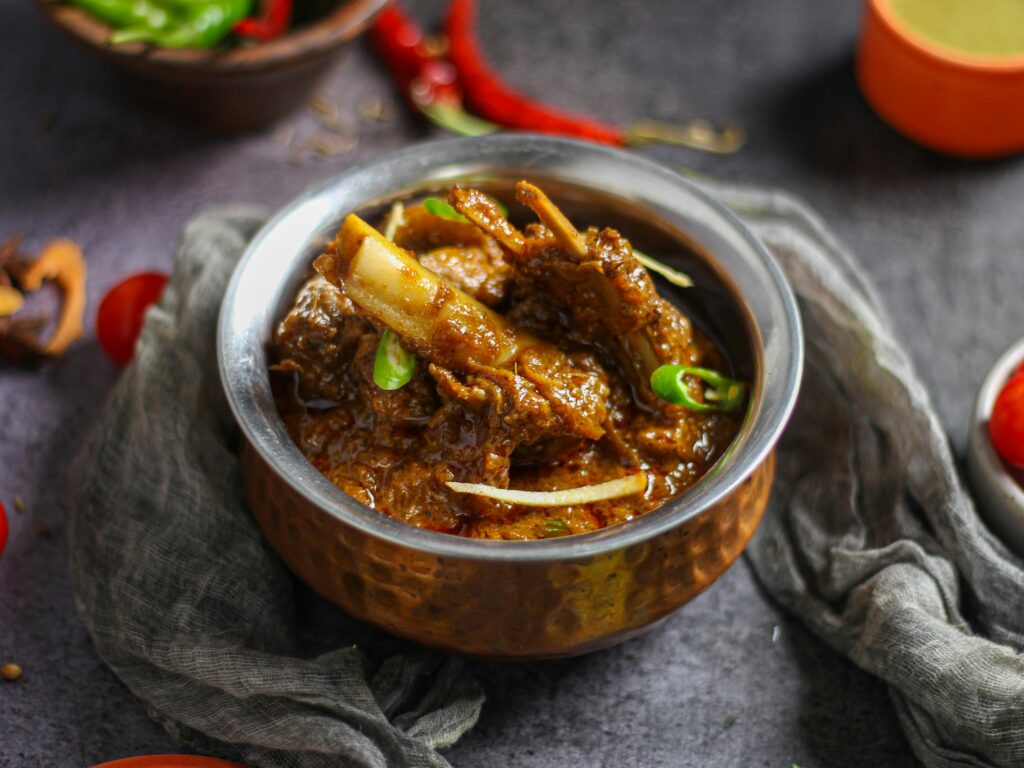 Close-up of a spicy mutton curry served in a traditional copper bowl, showcasing rich Indian flavors.